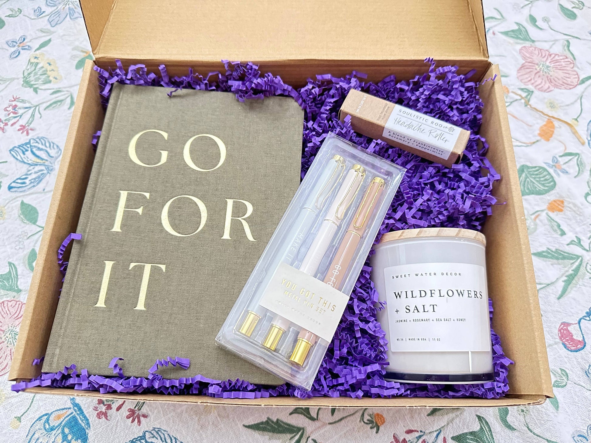 Eco-friendly gift box including a journal, 3 pen set, wildflowers, headache essential oil roller, and salt soy candle.